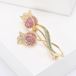 Close-up of elegant double tulip brooch with pink zircon stones and green crystals