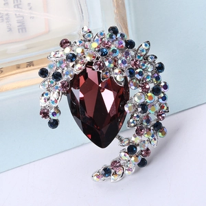 Detail of luxury crystal brooch with a deep red pear-cut stone and colorful rhinestones