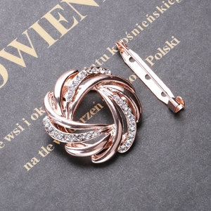 Close-up of rose gold spiral brooch with rhinestones and metal safety pin clasp