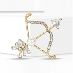 Détail d'une broche flèche dorée avec cristaux blancs et perle centrale pour costume