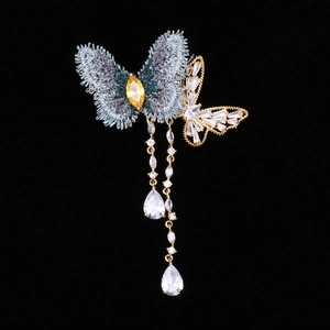 Détail macro de la broderie et des zircons étincelants sur la broche papillon