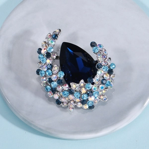 Macro shot of a luxury crystal brooch with teardrop blue stone on a marble tray