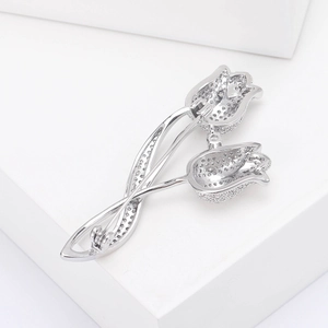 Detailed macro view of silver tulip brooch with micro-set zircon on white stone