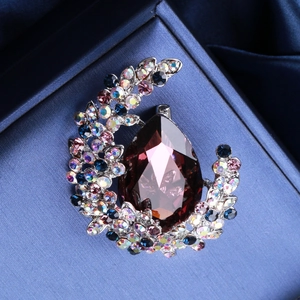 Luxury water drop crystal brooch with purple gemstone on blue silk velvet background