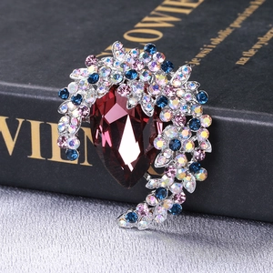 Detail of luxury crescent brooch with large teardrop amber stone and colorful crystals