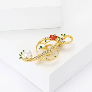 Détail de la broche note de musique avec rose rouge, feuilles vertes et perle blanche