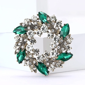 Détail macro d'une broche fleur dorée avec des gemmes vertes et des strass étincelants