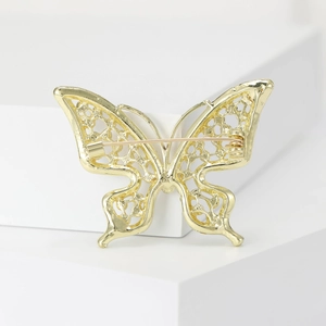 Détails du dos d'une broche papillon dorée montrant le travail du filigrane et l'épingle
