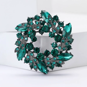 Détail de la broche couronne en strass verts avec cristaux marquise sur base en métal