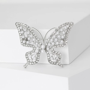 Détail de broche papillon avec perles blanches et strass scintillants sur base argentée