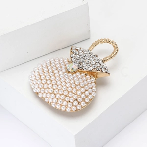Elegante goldene Handtaschen-Brosche mit Perlen und Kristallen auf weißem Marmorstein
