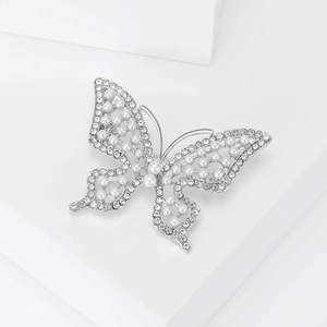 Broche papillon élégante avec perles et strass sur un fond géométrique blanc