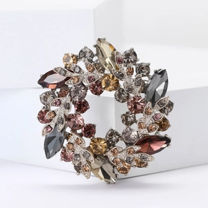 Vue détaillée d'une broche couronne élégante sertie de strass colorés sur socle blanc