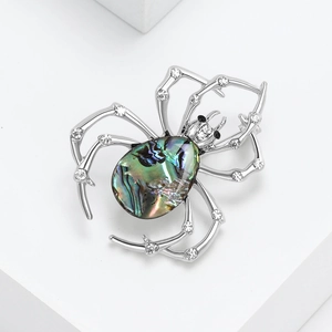 Vintage spider brooch with iridescent abalone shell and sparkling crystals on white base
