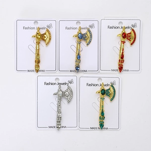 Detailed view of axe-shaped alloy brooches with vibrant rhinestones on display cards
