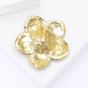 Détail de l'arrière d'une broche fleur dorée montrant le fermoir et la texture métal