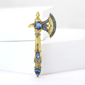 Close-up of golden axe brooch with blue rhinestones on white geometric stand