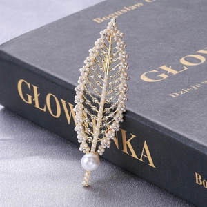 Detailed close-up of leaf brooch with gold alloy, rhinestones and elegant pearls