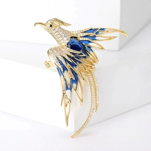 Luxurious phoenix brooch with blue enamel and sparkling cubic zirconia on a white pedestal
