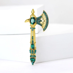 Detail of axe brooch with gold alloy base and green crystals on white geometric stand