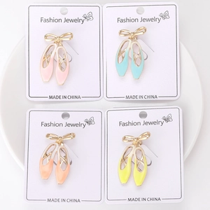 Vue détaillée de quatre broches chaussons de ballet colorées avec des nœuds dorés