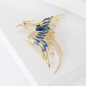 Detailed close-up of a phoenix brooch with gold plating and blue enamel feathers