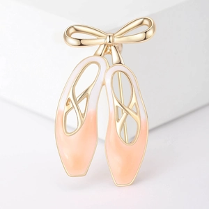 Détail de la broche chaussons de danse en émail rose avec un nœud doré poli