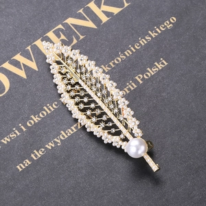 Detailed macro view of the golden leaf brooch with white pearls and sparkling crystals