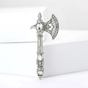 Detailed view of silver axe brooch featuring crystal rhinestones on white display
