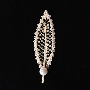Macro shot of gold leaf brooch featuring white pearls and sparkling crystal details