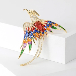 Close-up detail of luxury phoenix brooch with colorful enamel feathers and red zircon