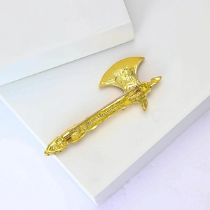 Detailed back view of a gold axe brooch showing the secure safety pin and alloy texture