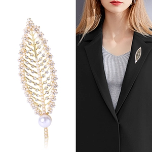 Elegant gold leaf brooch with white pearls and rhinestones shown on black suit jacket