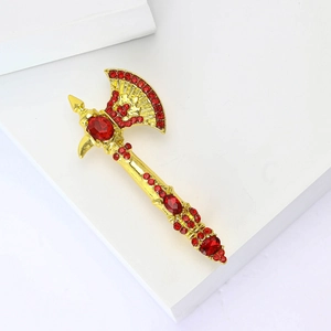Elegant gold axe brooch with red rhinestones and rubies on a white geometric stand