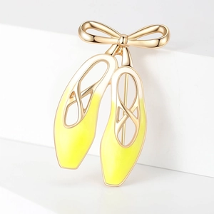 Macro d'une broche de chaussons de danse avec métal doré et émail dégradé jaune