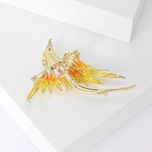 Detailed macro shot of phoenix brooch featuring yellow gradient enamel and large crystal