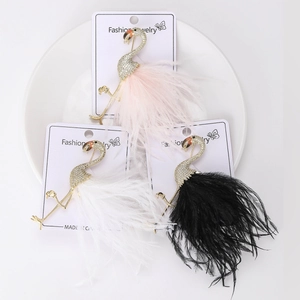 Vue détaillée de trois broches flamants roses avec zircons et plumes dans un plat blanc