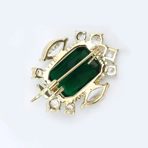 Macro shot of vintage emerald brooch back showing safety pin clasp and hollow metalwork