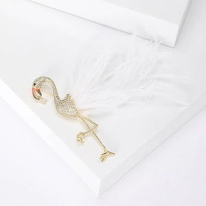 Détail d'une broche flamant rose avec plumes blanches, dorure et incrustations de cristal