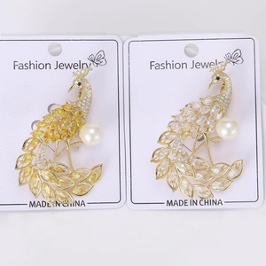 Macro detail of luxury peacock brooches with cubic zirconia and large white pearls