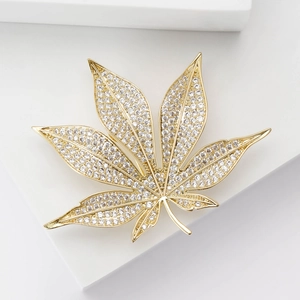 Eleganter goldener Ahornblatt-Anstecknadel mit Zirkonia auf weißem Stein