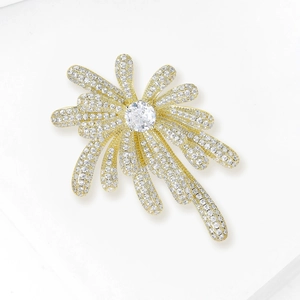 Elegant gold fireworks brooch with micro-pave zircons and central crystal on white background