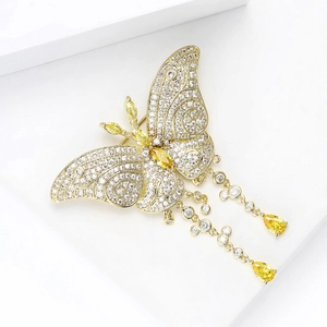 Détail d'une élégante broche papillon avec cristaux jaunes et pompons sur fond blanc