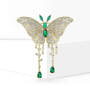 Broche papillon dorée avec des ailes en zircon, pierres émeraude et chaînes à pompons