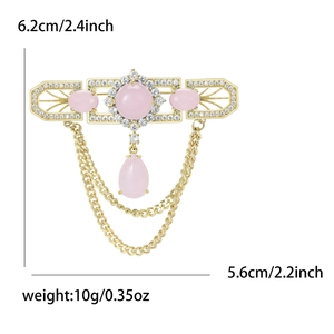 Detailed view of luxury gold brooch with pink stones and dimensions of 6.2cm by 5.6cm
