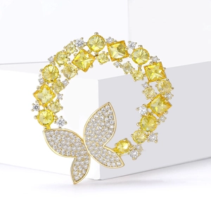 Gros plan sur la broche couronne papillon dorée avec zircons jaunes et blancs