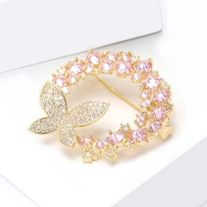Détail d'une broche couronne papillon dorée avec cristaux roses et pierres de zircone cubique
