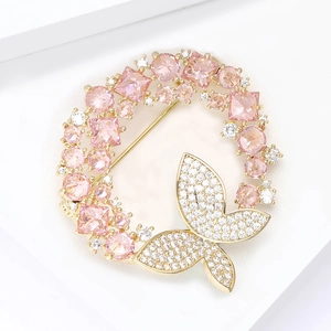 Vue détaillée de la broche couronne en zircon rose avec détail papillon pavé de brillants