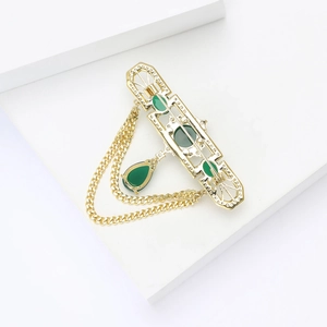 Detailed back view of vintage gold brooch with green stones and hanging cuban chains