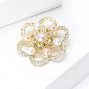 Elegant gold camellia brooch with freshwater pearls and sparkling zircons on a stand